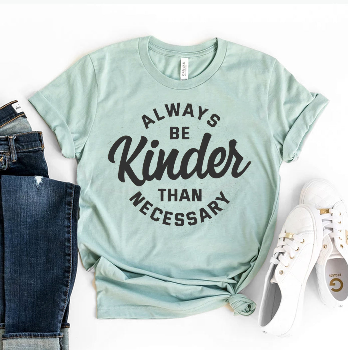 A women's T-shirt with the phrase "Always Be Kinder Than Necessary" printed on the front.