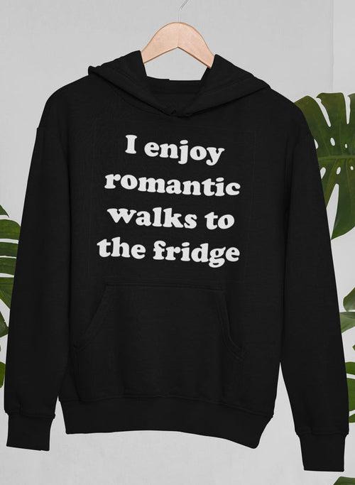 A cozy black hoodie with the playful slogan "I Enjoy Romantic Walks To The Fridge" printed on the front in white font, combining humor with motivation. Designed for women, this comfortable hoodie encourages positivity and lighthearted self-expression.